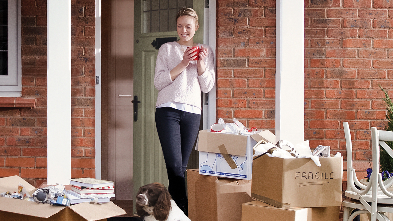 Redrow - Inspiration - Woman drinking tea while moving home with many boxes and a dog