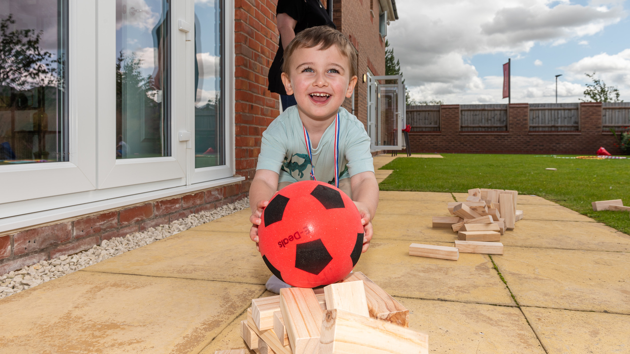 Redrow - Inpiration - Small boy with red football in the garden